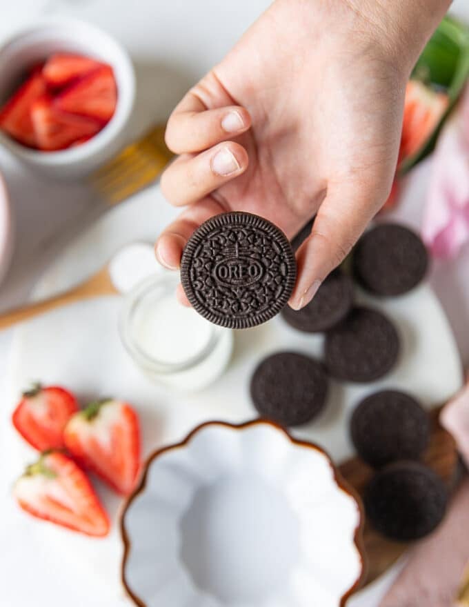A hand holding the oreo cookie to be used which is the regular one, not the thick or double cream or chocolate fudge or any other variation 