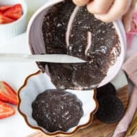 A hand pouring the batter into a ramekin