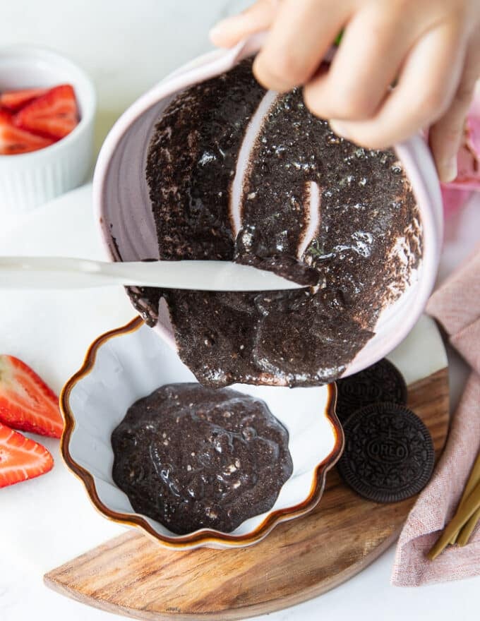 A hand pouring the batter into a ramekin