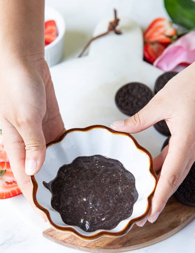 A hand holding the ramekin and ready for the microwave