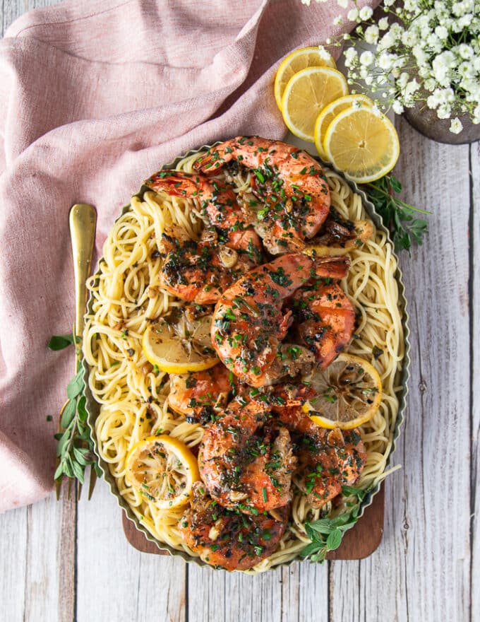 perfect shrimp scampi served over spaghetti and garnished with lemon slices and herbs