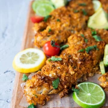 close up of one baked haddock surrounded by lime wedges