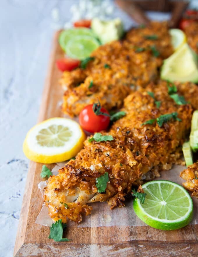 close up of one baked haddock surrounded by lime wedges 