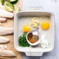 A tray with the egg coating which has ingredients in small bowls including cilantro, egs, lemon juice, garlic, spice blend and lime juice