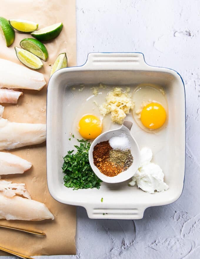 A tray with the egg coating which has ingredients in small bowls including cilantro, egs, lemon juice, garlic, spice blend and lime juice