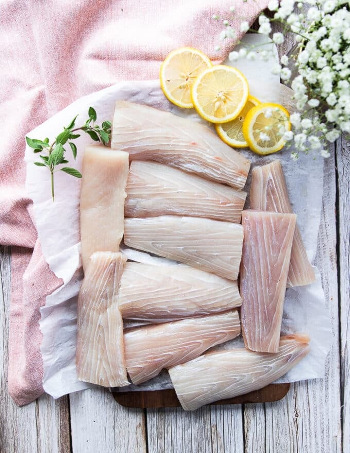 A board with fillets of mahi mahi patted dry and fresh or defrosted, surrounded by lemon slices 