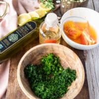 ingredients for a citrus vinaigrette in a bowl with herbs, orange juice, olive oil, vinegar