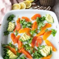 orange avocado salad base for the grilled mahi mahi on a plate with avocado slices , orange segments and arugula