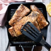 A hand showing one piece of mahi mahi fish ready to flip on the grill