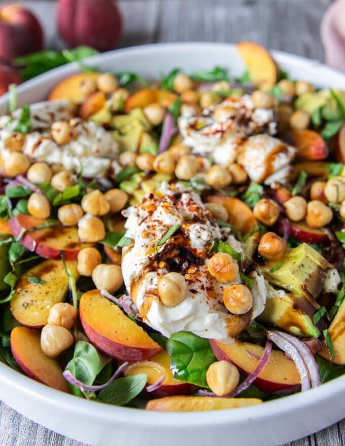 close up of the final dressed peach burrata salad showing the peaches and creamy burrata with a balsamic glaze 