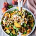 two hands serving some peach burrata salad with serving spoons showing close up of the burrata and peaches and balsamic dressing