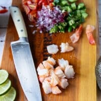 A knife dicing the shrimp on a cutting board into 1 inch pieces