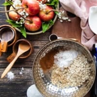 The ingredients to make the oat topping for the apple crisp on a board including oats, sugar, flour, cinnamon, butter