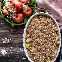 The oat crisp topping is added all over the apples in the baking dish and now the apple crisp is ready to bake