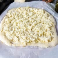 A thin layer of mozzarella cheese is added over the dough to make the pizza extra cheesy--optional