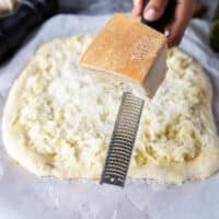 a hand grating freshly grated pecorino cheese