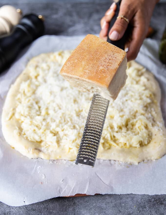 a hand grating freshly grated pecorino cheese