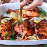 A hand holding a fork and showing a bite of honey glazed salmon recipe