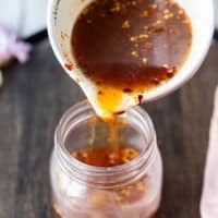 Hot honey sauce ready and being poured from the sauce pan into a jar