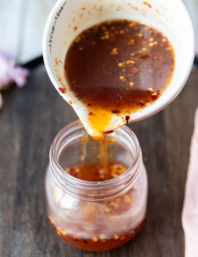 Hot honey sauce ready and being poured from the sauce pan into a jar