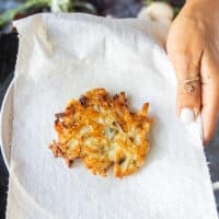 Cooked potato pancakes draining on paper towels after being removed from the skillet