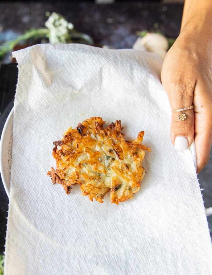 Cooked potato pancakes draining on paper towels after being removed from the skillet