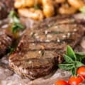 Close up of a ribeye steak cooked perfectly on the grill with grill mark and some melted butter on top