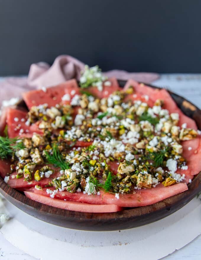 Side view of a carpaccio recipe showing the detailed toppings and watermelon slices