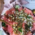 A hand holding a spoon with watermelon carpaccio showing how to serve it