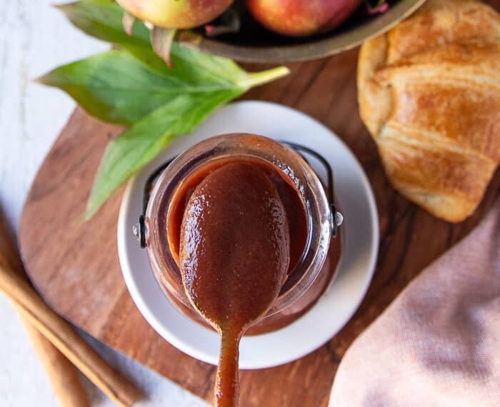 A spoon scooping apple butter from the jar showing close up of the thick and smooth texture