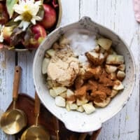 The apple butter ingredients: white sugar, brown sugar, cinnamon and salt added to the bowl of diced apples.