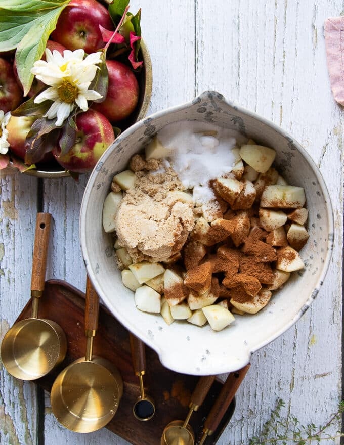 The apple butter ingredients: white sugar, brown sugar, cinnamon and salt added to the bowl of diced apples.