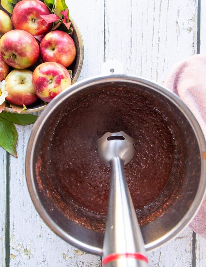 An immersion blender pureeing the apple butter until smooth