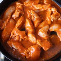 The chicken and sauces are all added into a heavy cast iron skillet with sauce and everything