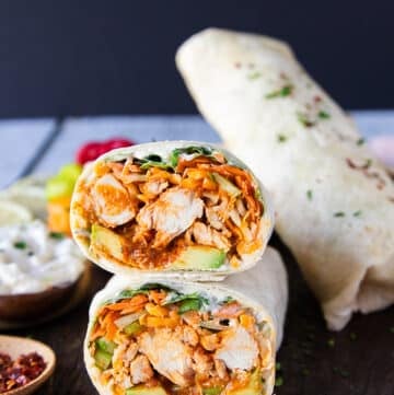 close up of a cut up buffalo chicken wrap showing the inside layers of buffalo chicken, veggies cheese, sauce wrapped in tortilla