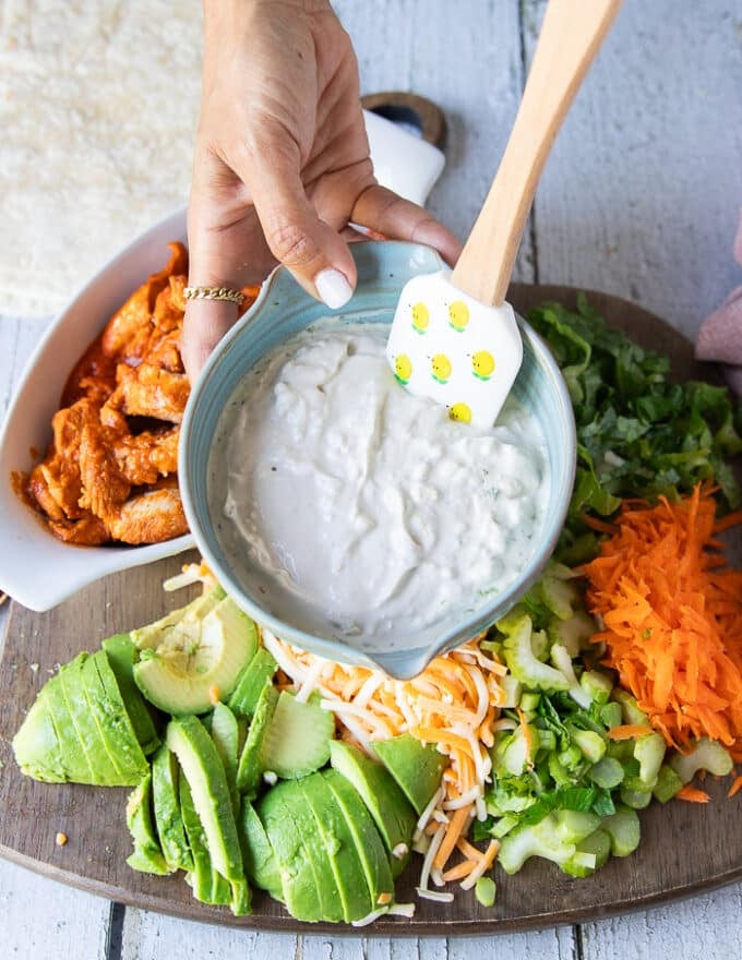 A hand holding a bowl of blue cheese dressing prepared and ready