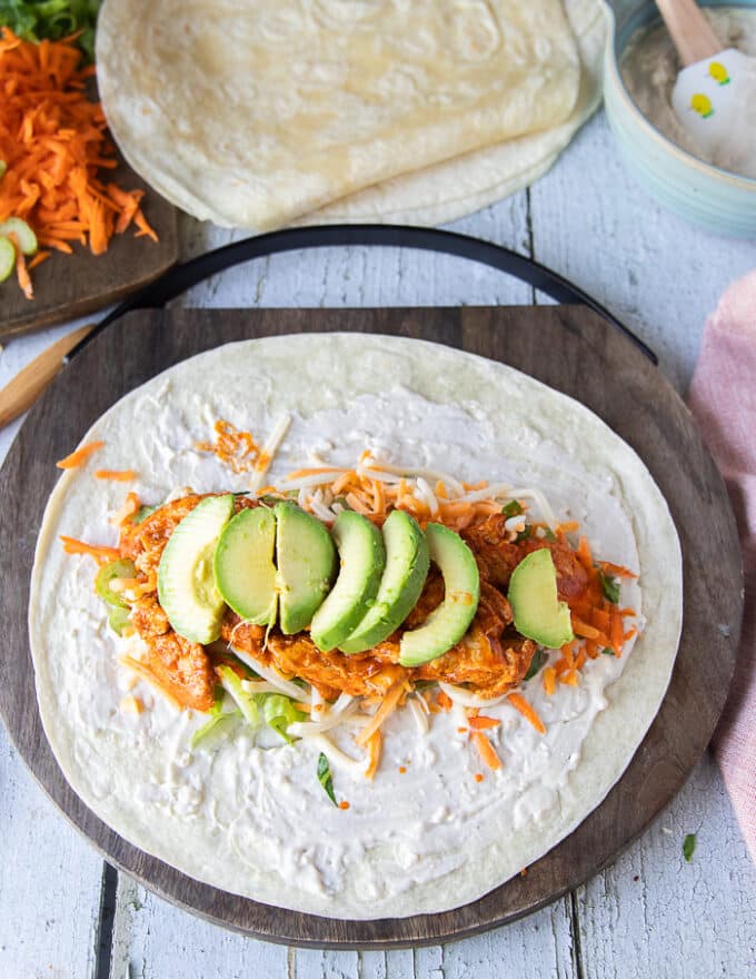 The final layer of the buffalo chicken wrap is the sliced avocados.