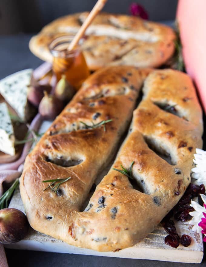 One Fougasse bread on a white board close up showing the add ins and the golden bread shaped like a leaf