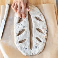 Tip: A hand opening the slits gently made ont he dough to make sure they remain slits and not seal as the dough rises again.