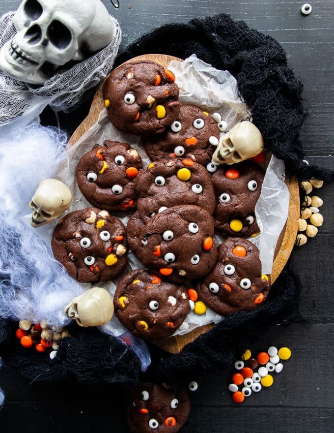 The Halloween Cookies baked and placed in a spooky setup surrounded by skulls, more candy eyes, a large skull and some white web