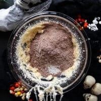 The dry ingredient bowl of cocoa powder flour baking soda is added to the creamed sugar, butter and egg bowl