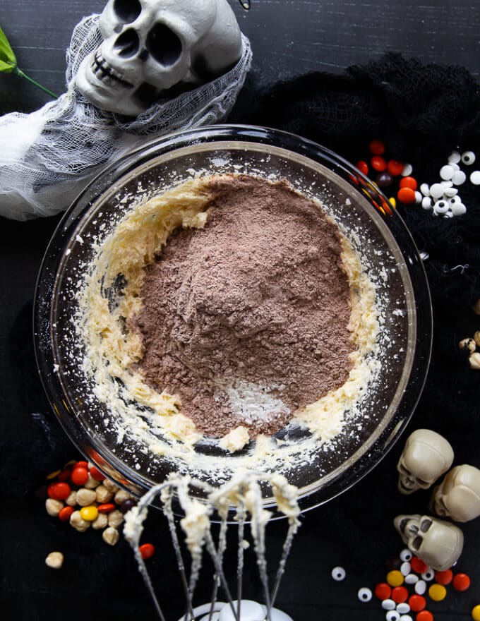 The dry ingredient bowl of cocoa powder flour baking soda is added to the creamed sugar, butter and egg bowl