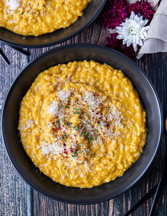 close up of one plate of risotto garnished with parmesan cheese, fresh thyme and chili flakes