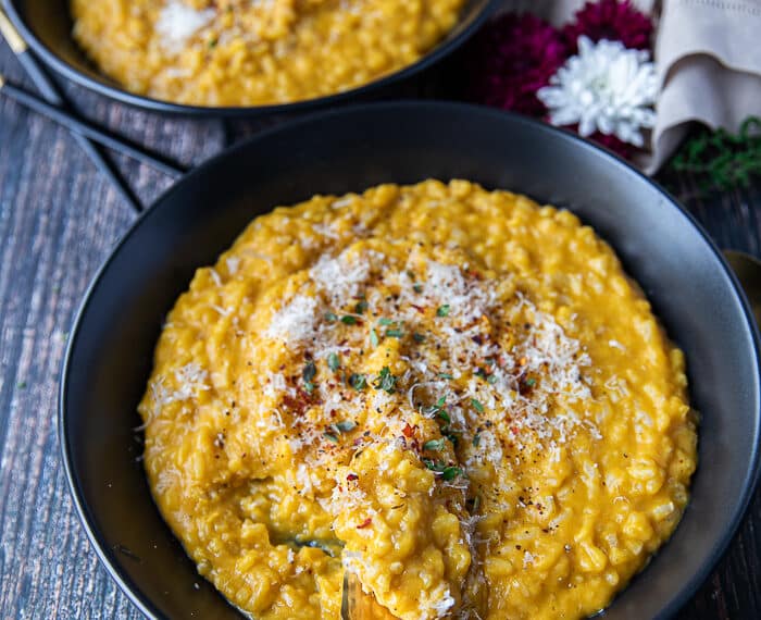A plate of pumpkin risotto with a fork swirling it to show the texture of the risotto