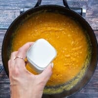 A hand adding in milk to the risotto pot for a creamier risotto