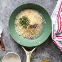 A small skillet with panko, herbs, garlic, olive oil and seasoning all added in