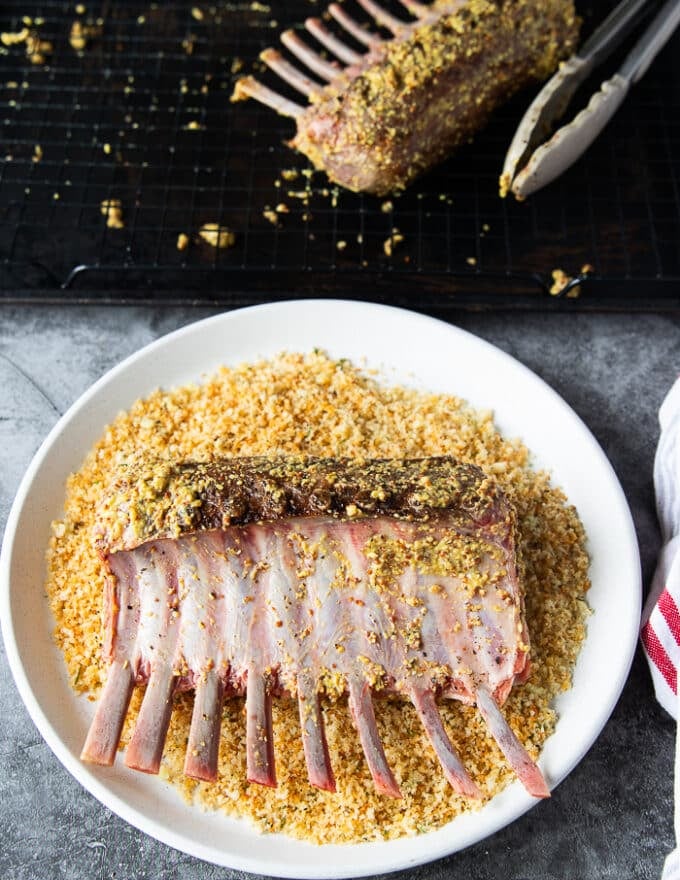 Rack of lamb dipped into a bowl of toasted breadcrumbs