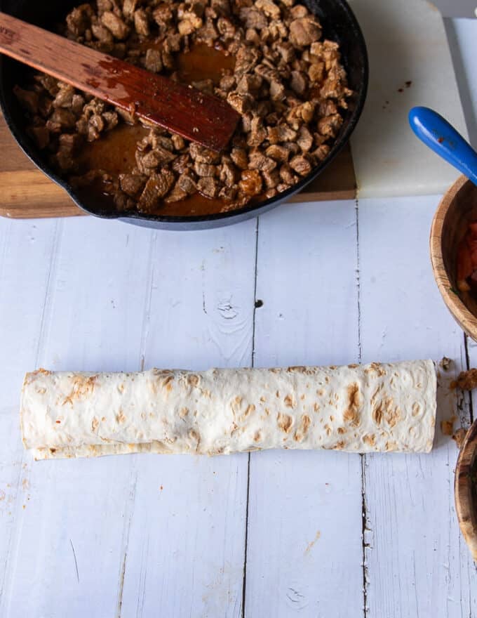 A rolled up Tantuni ready on a wooden board 