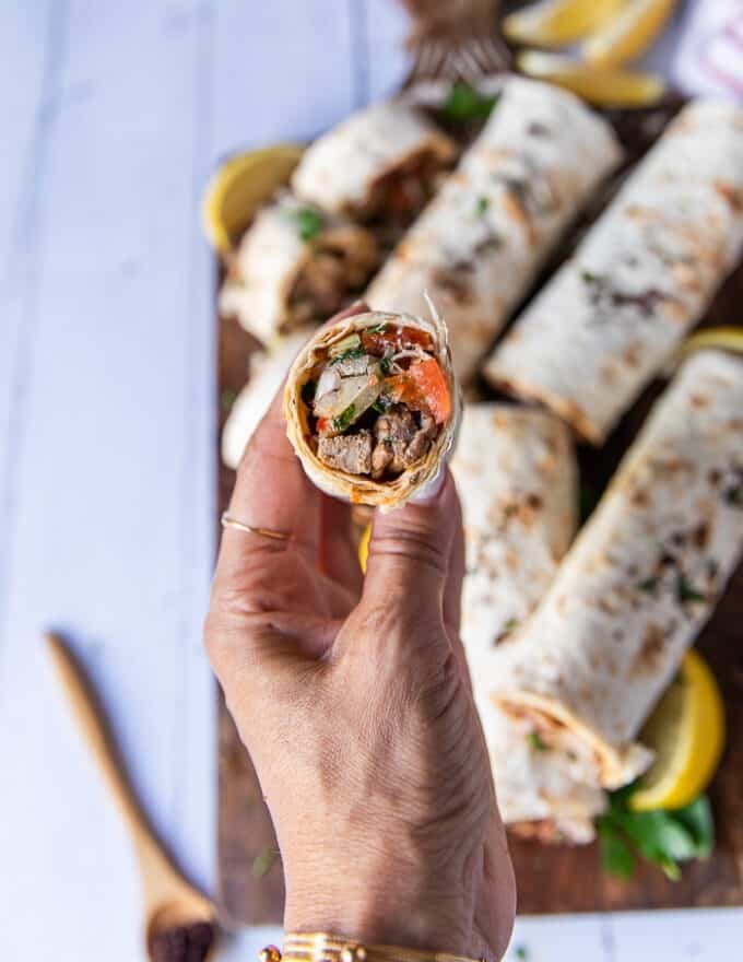 A hand holding a cut up tantuni close up to show the texture and filling 