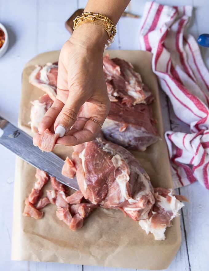 A hand holding a piece of cut up lamb to show the size